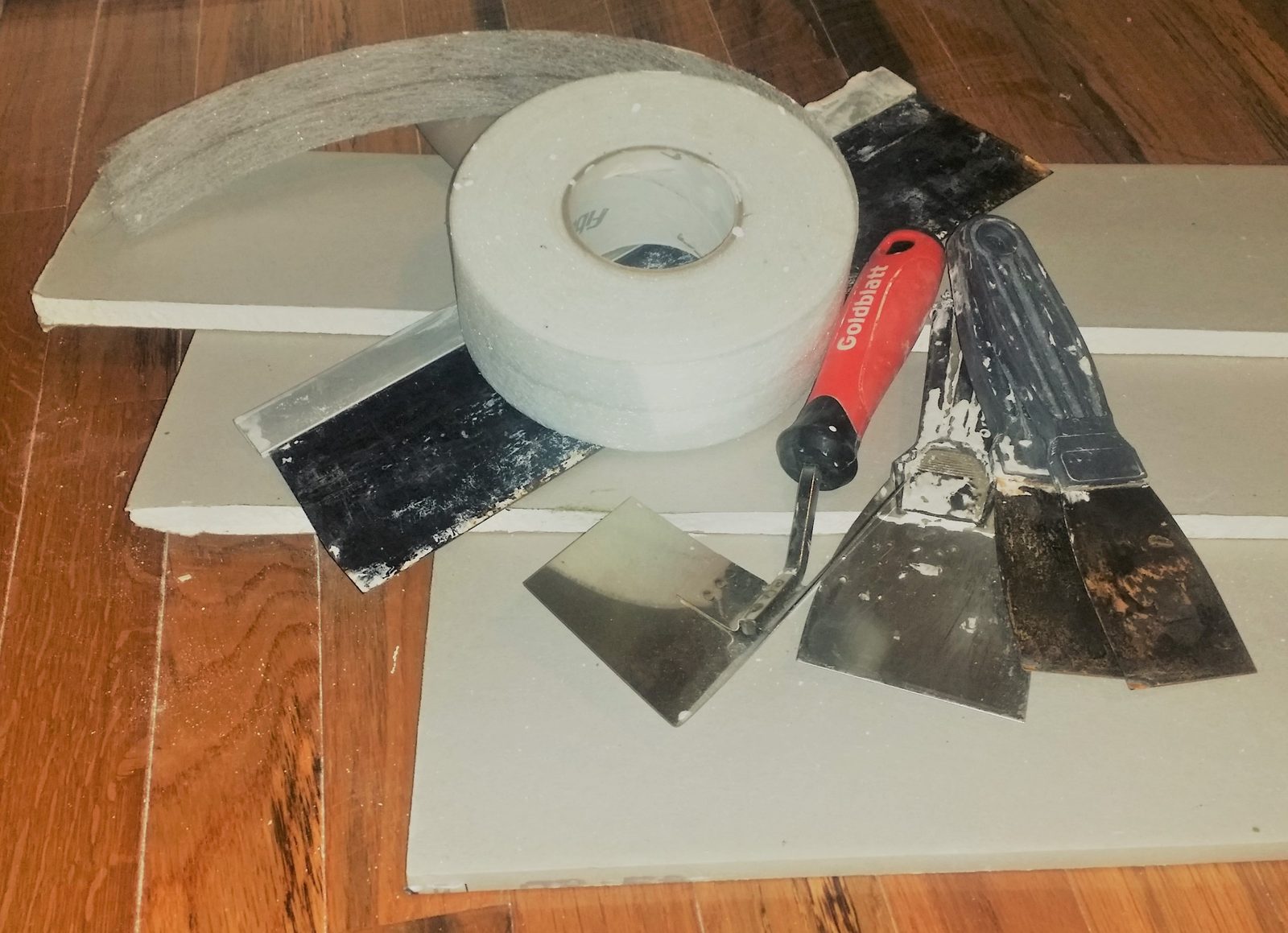 Drywall taping tools - joint knives, mud pan, and joint tape - ready for a Baltimore drywall repair